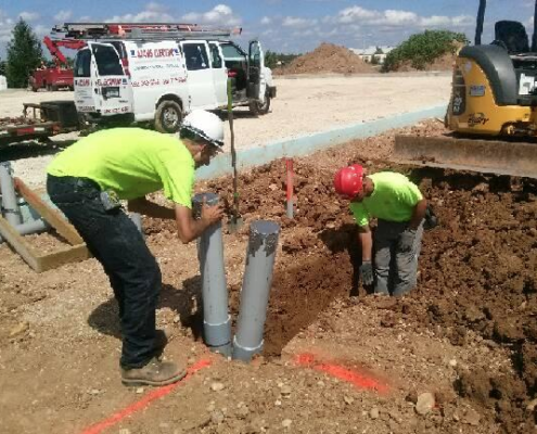 Two workers install water pipes.